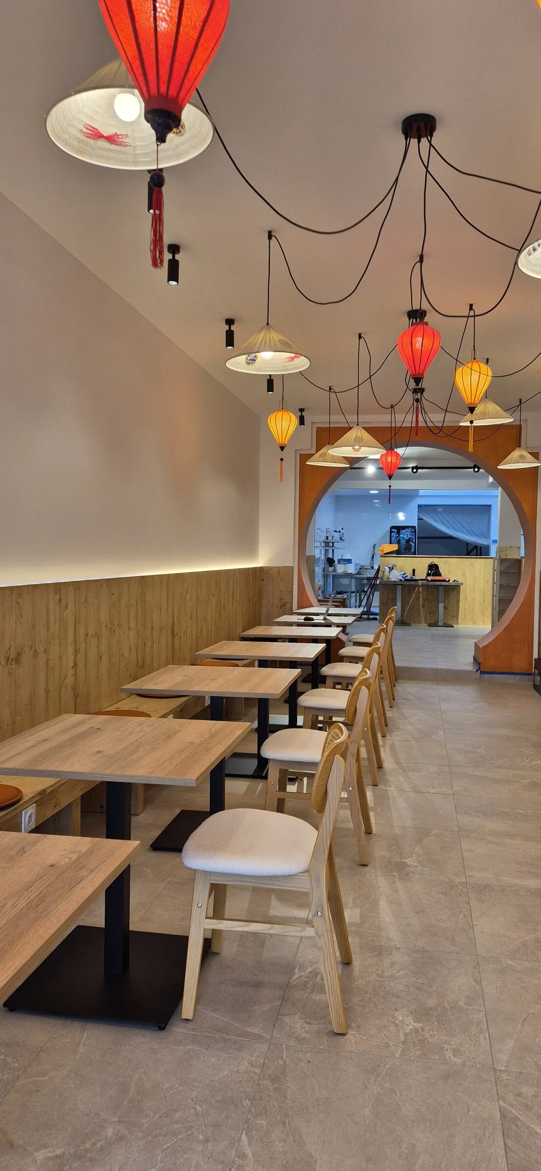 La salle de TORII : tables en bois, lanternes rouges et porte ronde