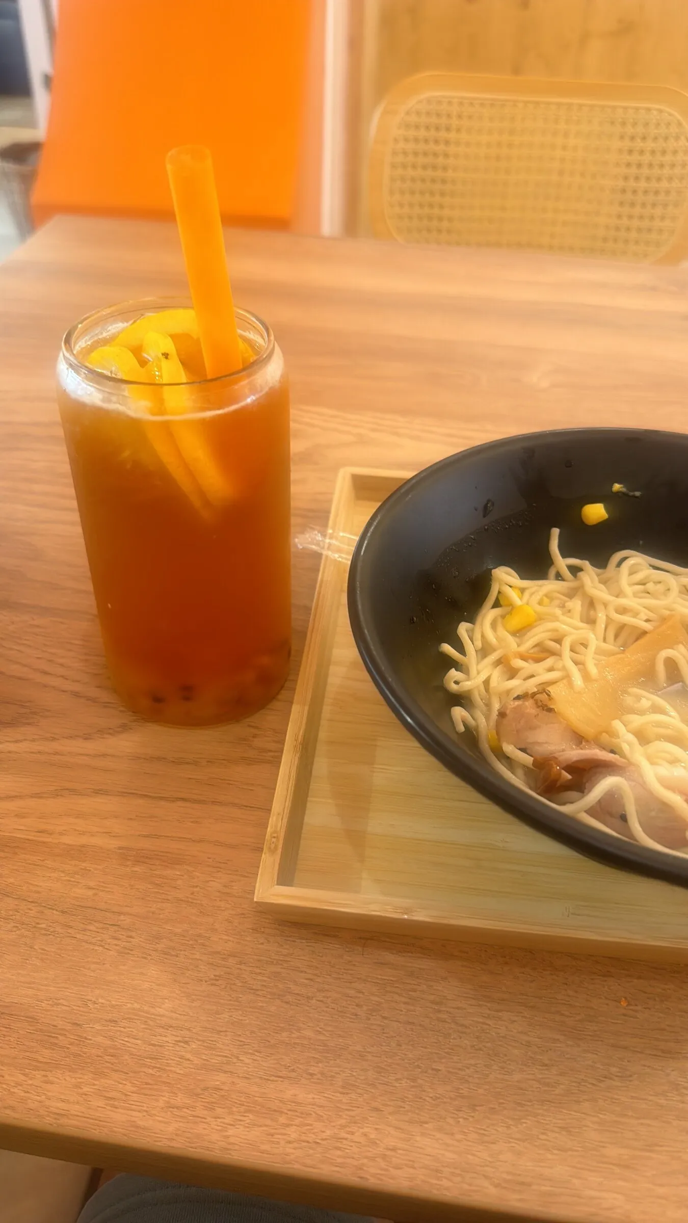 Un bol de ramen et un thé glacé sur une table en bois de TORII